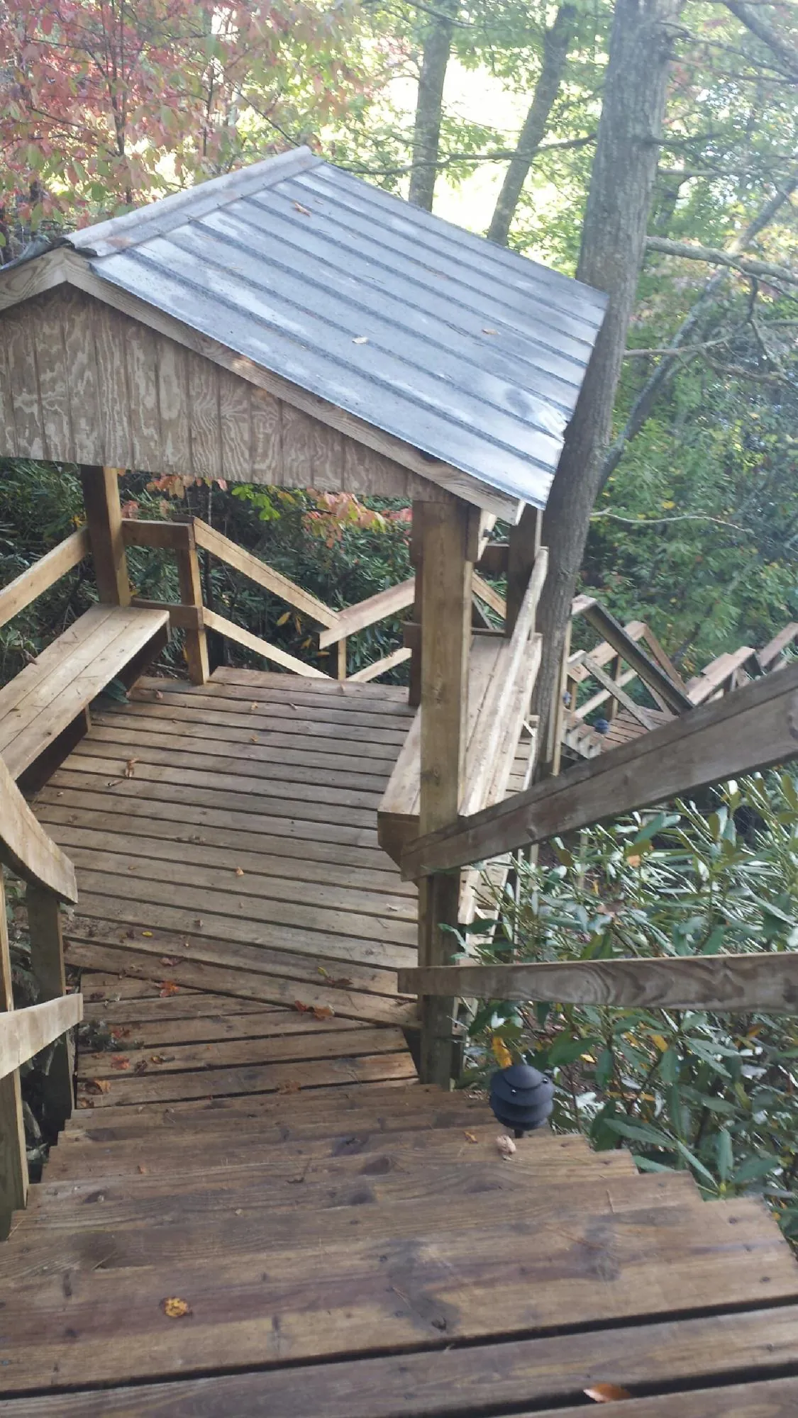 Metal roofed shelter over wooden steps on a wooded walkway — Skylight Repair & Installation work by our crew in Decker